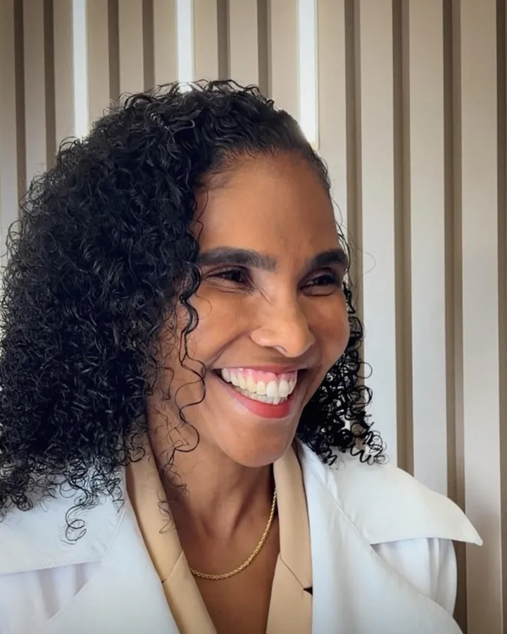 Dra. Rosana Frempong sorrindo, de jaleco branco, no consultório