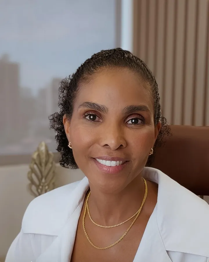 Dra. Rosana Frempong sentada à mesa do consultório, sorrindo
