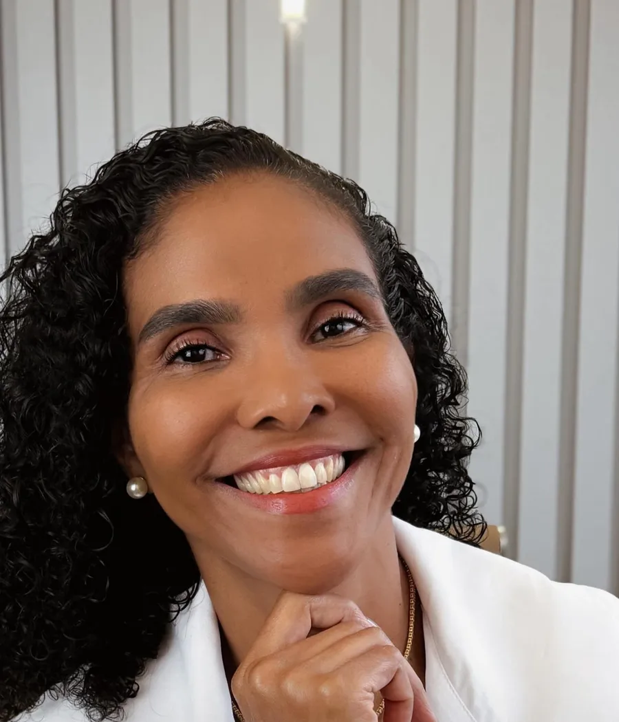 Dra. Rosana Frempong sorrindo, com a mão apoiada no queixo, de jaleco branco