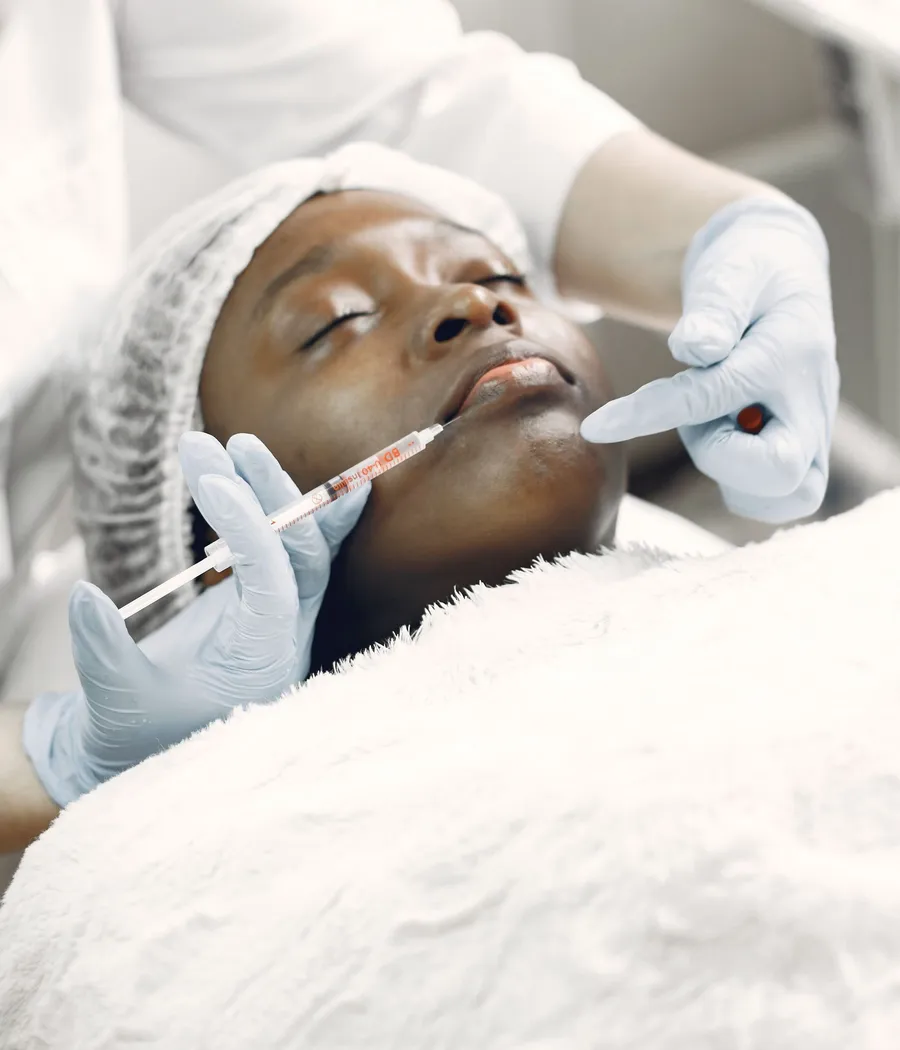 Paciente negra recebendo aplicação facial minimamente invasiva em ambiente clínico