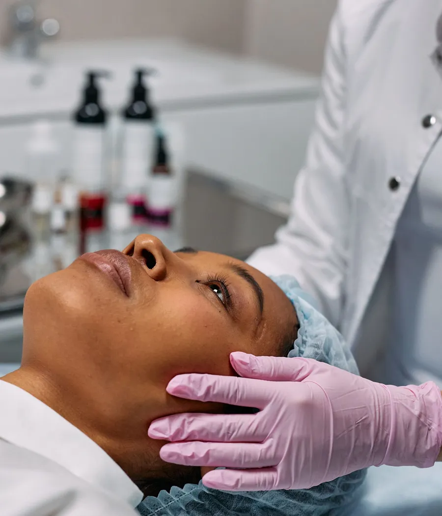 Profissional avaliando o contorno do rosto de uma paciente negra em ambiente clínico