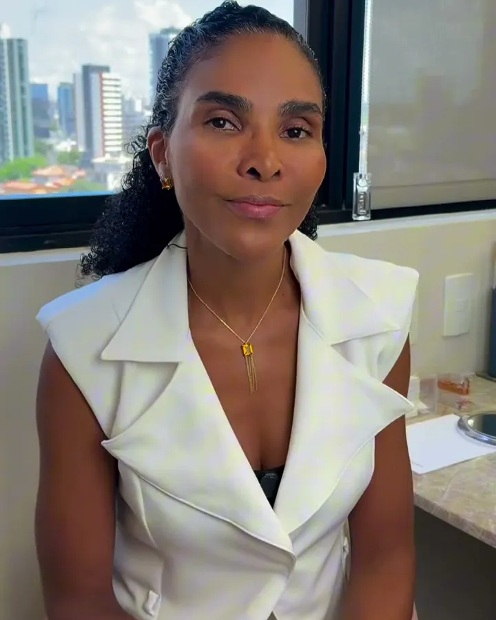 Dra. Rosana Frempong no consultório, com a cidade ao fundo pela janela